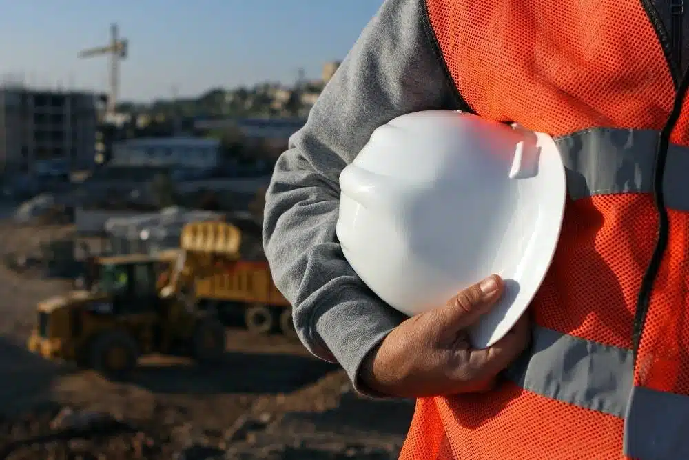 Worker holding a white hard hat on a construction site, representing what to do after a lost white card.