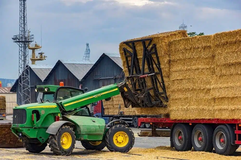 Telehandler loading hay bales onto a truck, showing the type of plant covered by telehandler licence training.