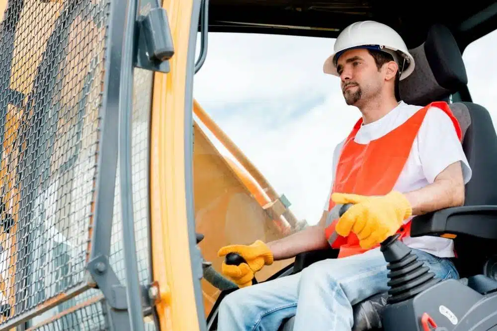 Construction worker operating machinery from inside a cab during crane operator training.